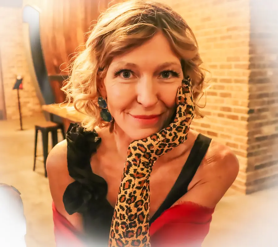 Portrait of Denise Choate, smiling, in a red dress and leopard-print glove